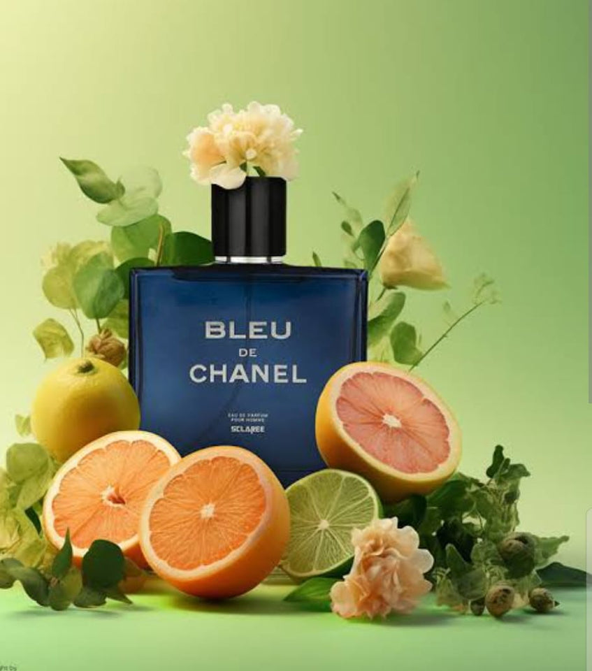 Bleu de Chanel perfume bottle surrounded by fruits and flowers on a green background