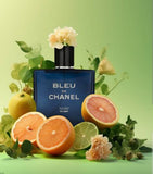 Bleu de Chanel perfume bottle surrounded by fruits and flowers on a green background