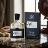 Creed Aventus perfume bottle and packaging on a marble surface